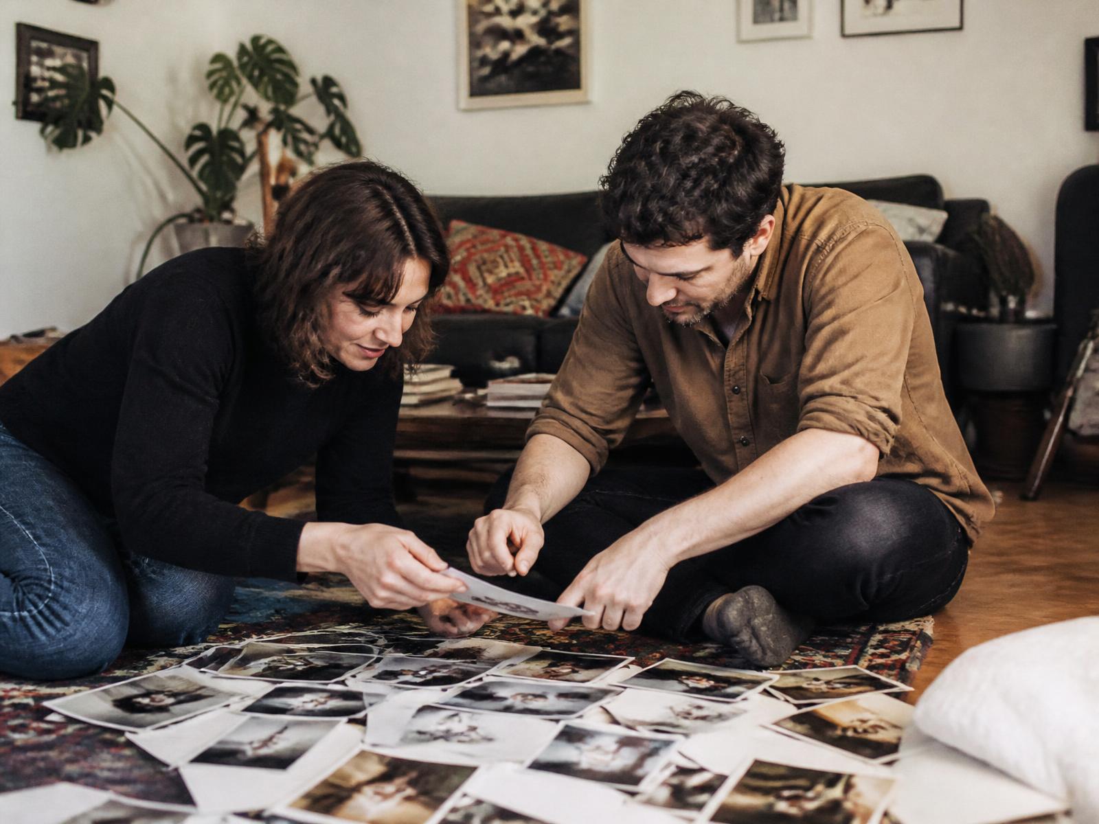 Two siblings sitting together looking through a box of old family photographs