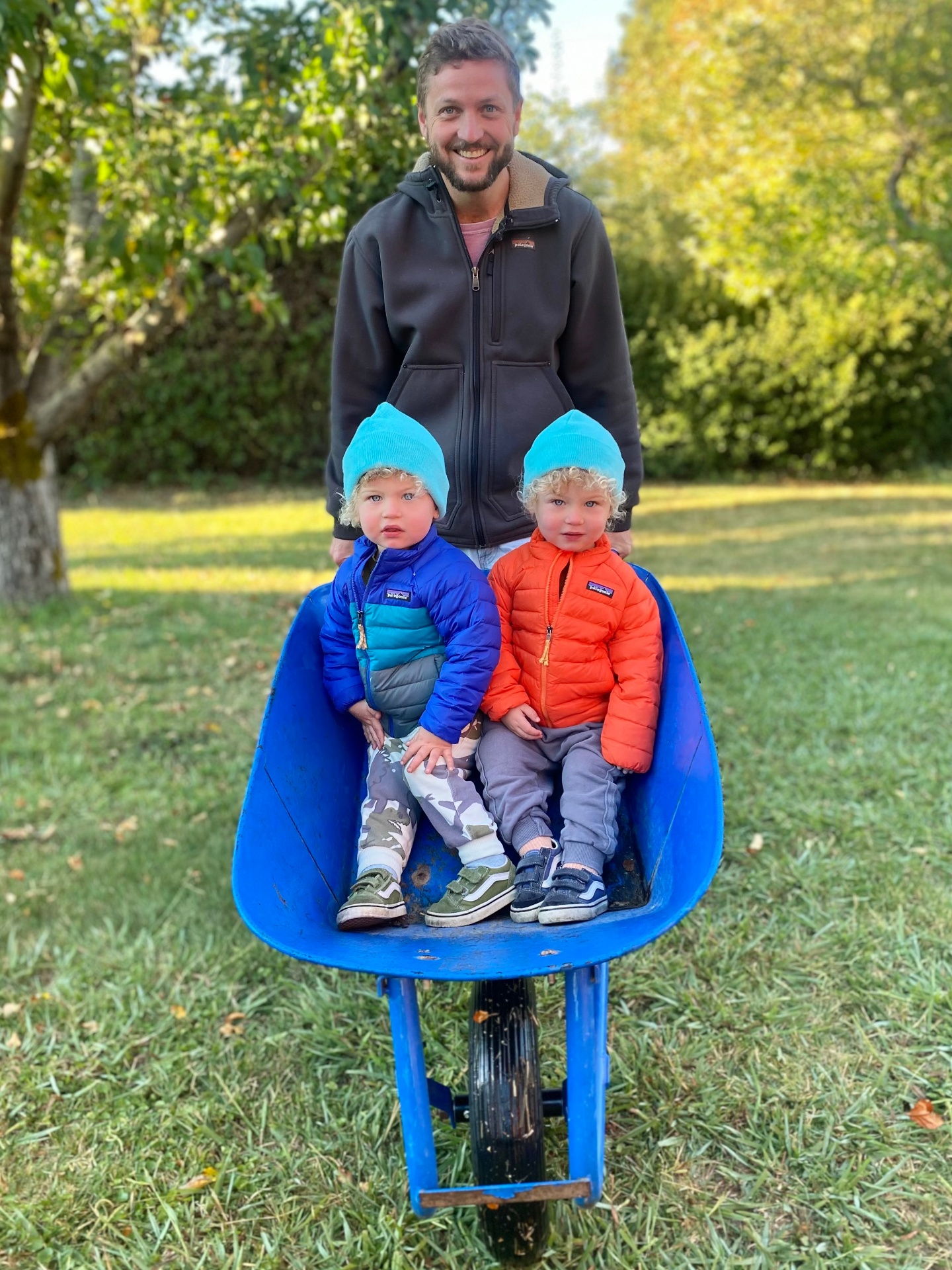 A vintage family photograph of a child being pushed in a wheelbarrow